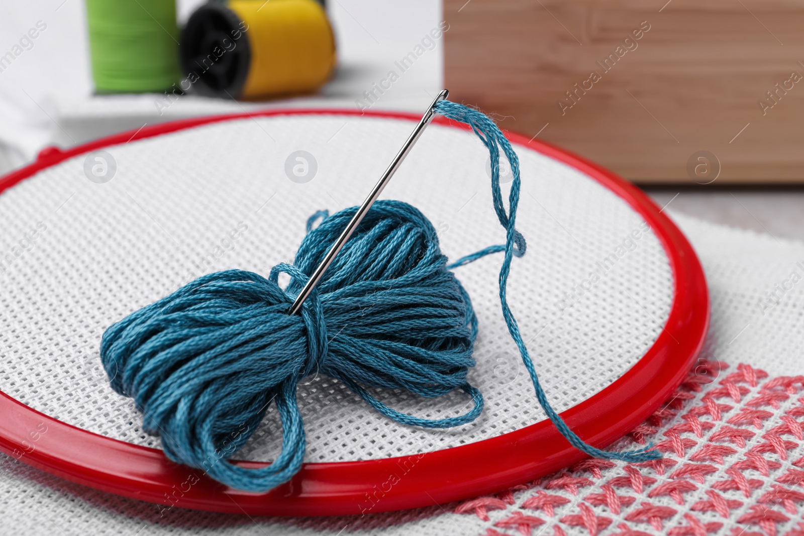 Photo of Embroidery hoop with fabric and needle on table, closeup