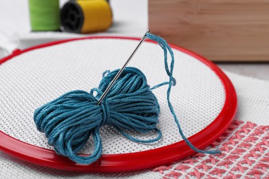 Photo of Embroidery hoop with fabric and needle on table, closeup