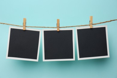 Photo of Wooden clothespins with empty instant frames on twine against light blue background. Space for text
