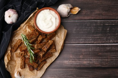 Photo of Crispy rusks with rosemary and sauce on wooden table, flat lay. Space for text