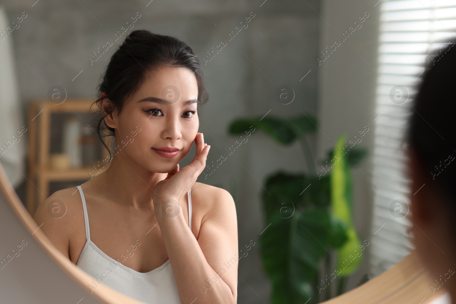 Photo of Portrait of beautiful woman near mirror indoors