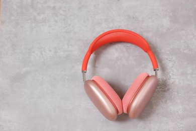 Stylish pink headphones on light grey table, top view. Space for text