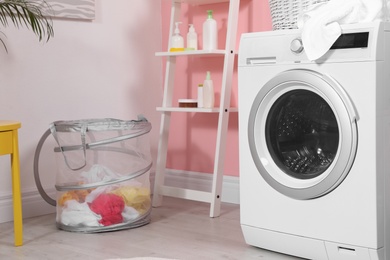 Photo of Modern washing machine near wall in laundry room