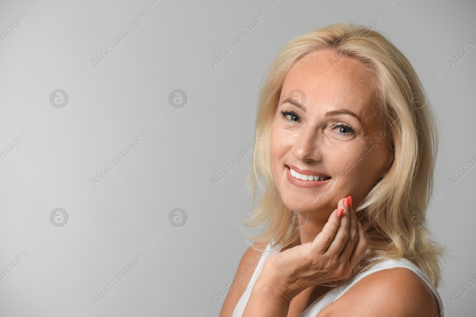 Photo of Portrait of beautiful mature woman with perfect skin on grey background. Space for text