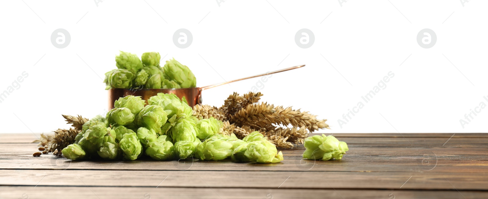 Photo of Fresh hop flowers and wheat ears on wooden table against white background, space for text