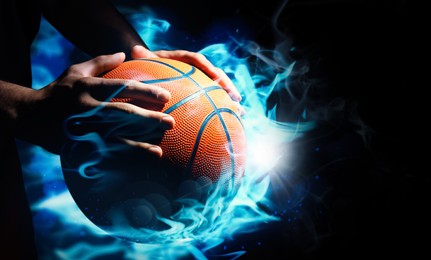 Image of Basketball player with ball in flame on black background, closeup 