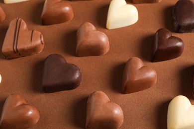 Beautiful heart shaped chocolate candies on brown background