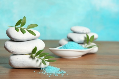 Photo of Spa stones, bamboo leaves and sea salt on table against color background