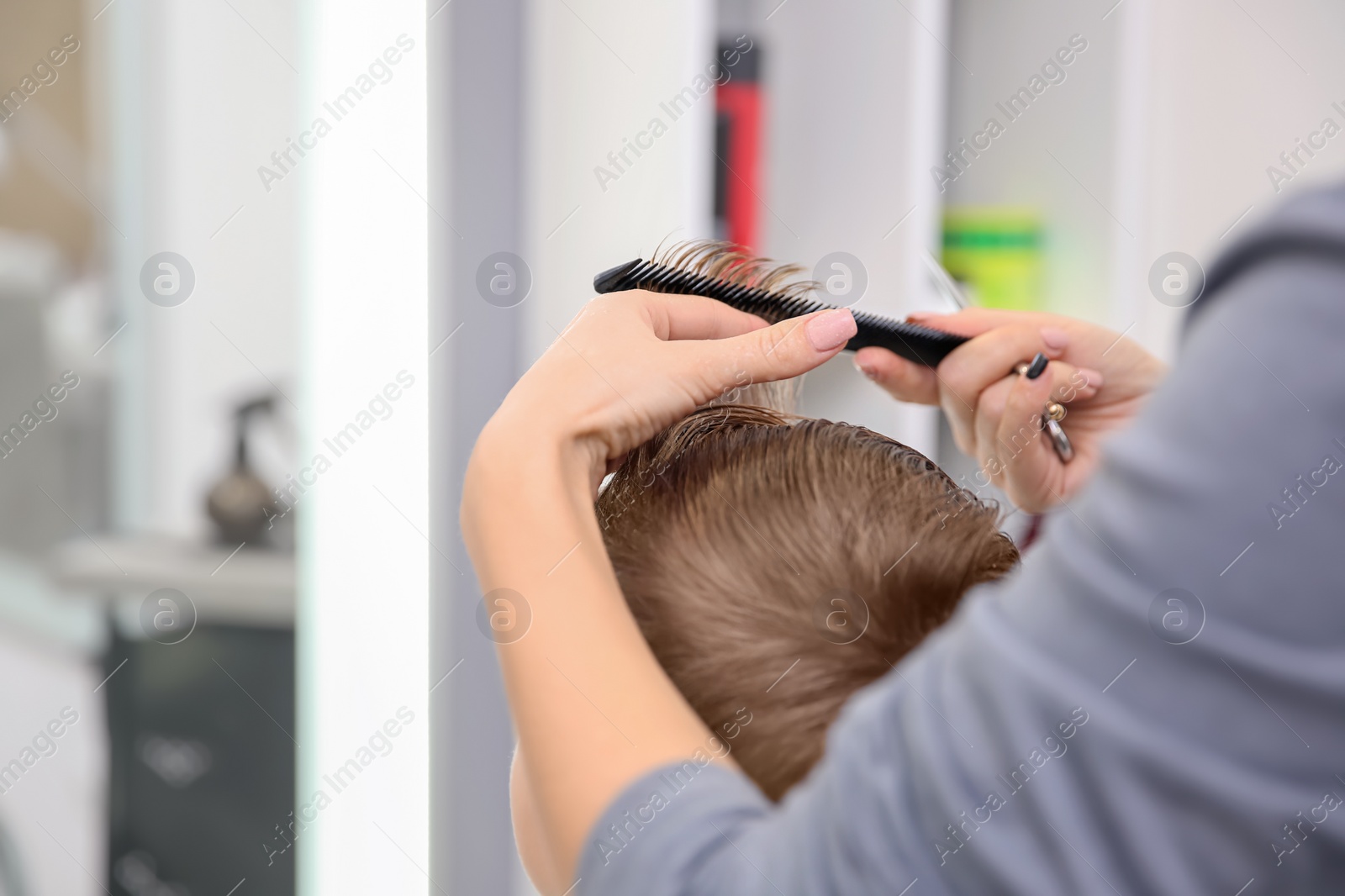 Photo of Professional female hairdresser working with little boy in salon