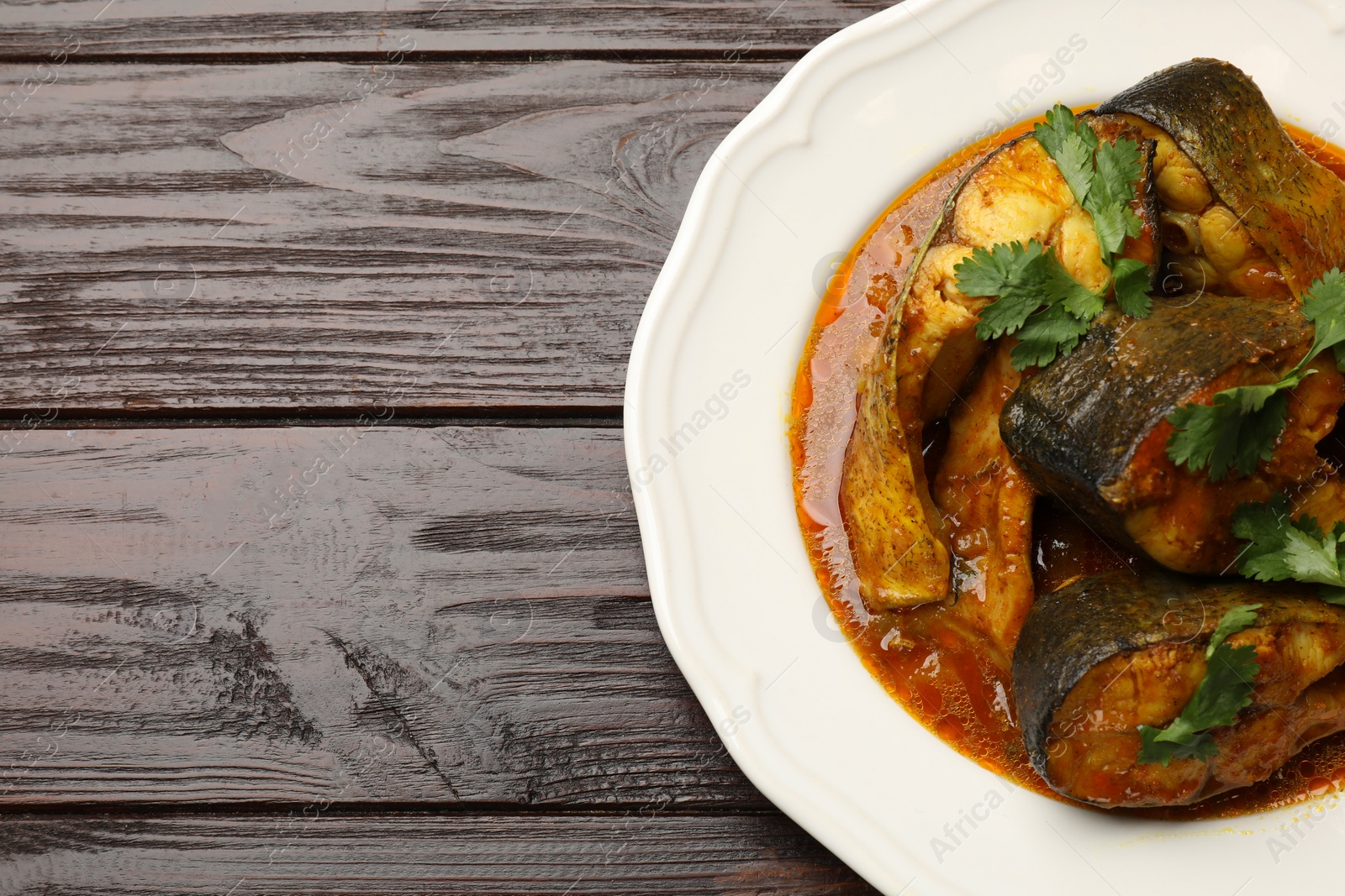 Photo of Tasty fish curry on wooden table, top view. Space for text. Indian cuisine