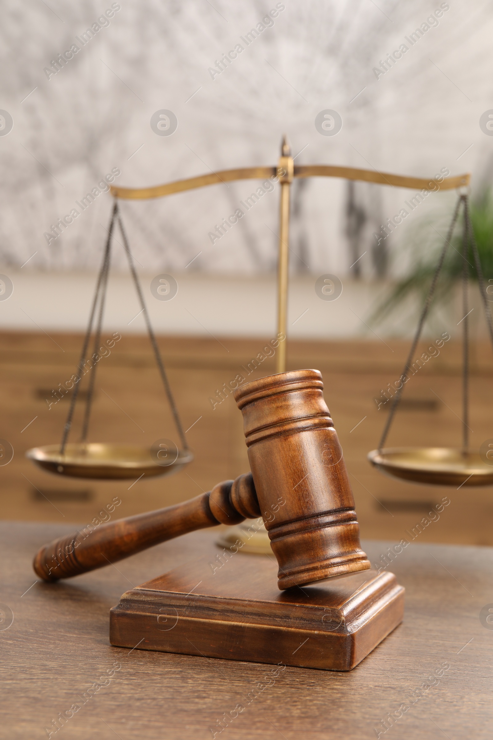 Photo of Wooden gavel, sound block and scales on table indoors