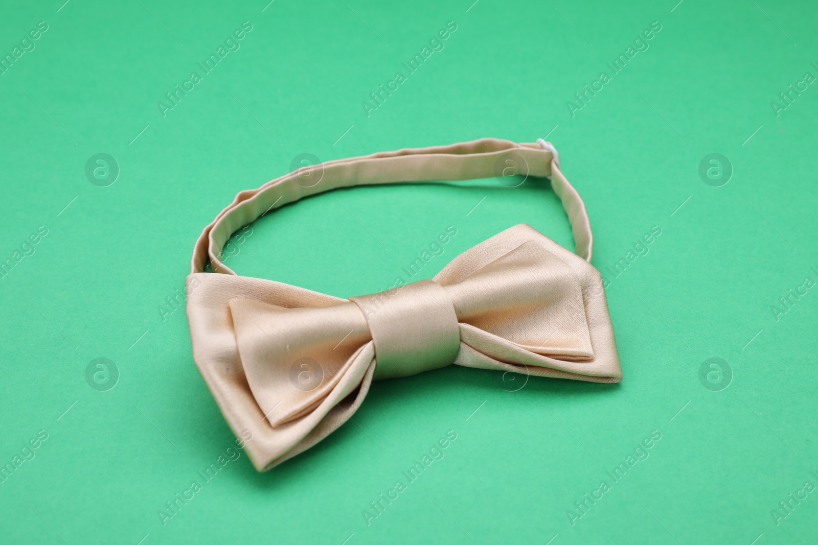 Photo of Stylish beige bow tie on green background
