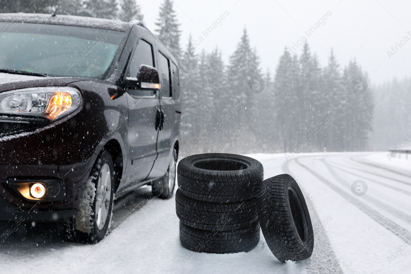 Image of Snow tires near car on road in winter