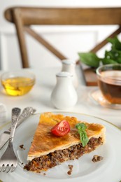 Photo of Piece of delicious pie with minced meat, tomato and basil served on white table