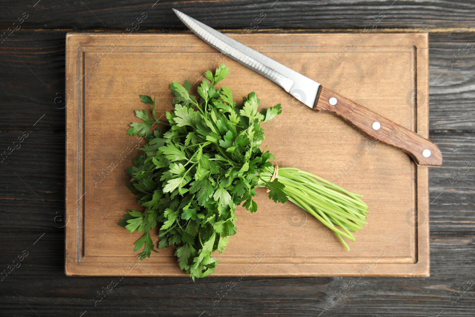 Photo of Board with fresh green parsley and knife on wooden background, top view