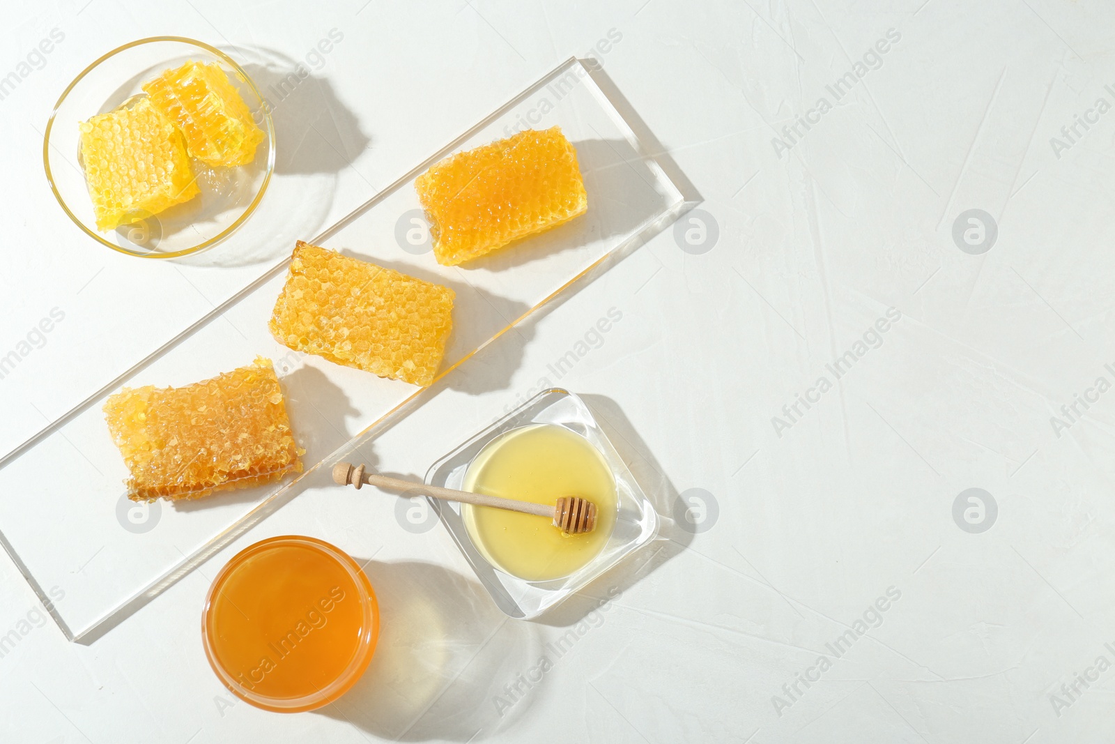 Photo of Natural honeycombs with tasty honey and dipper on white table, flat lay. Space for text