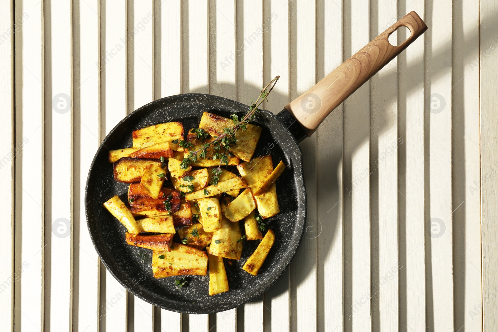 Photo of Delicious parsnips with thyme in frying pan on white wooden table, top view