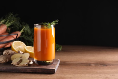 Photo of Glass of tasty carrot juice and ingredients on wooden table against black background, space for text