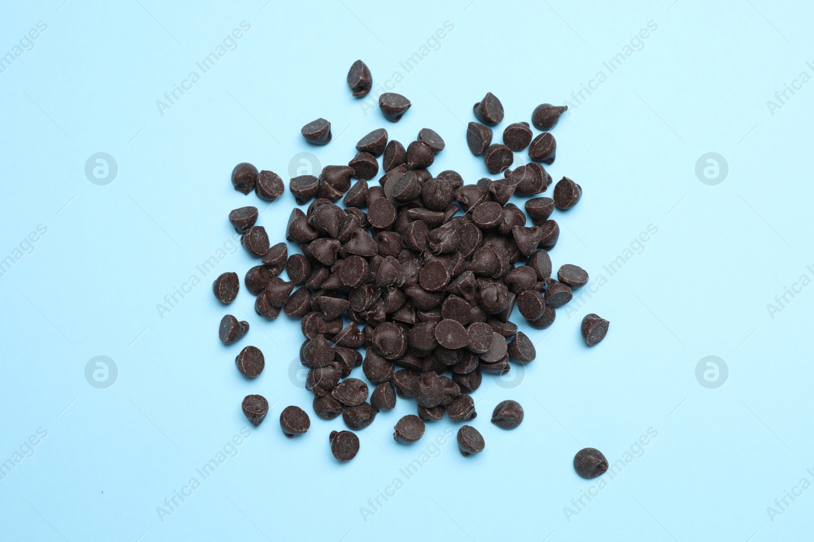 Photo of Pile of delicious chocolate chips on light blue background, top view