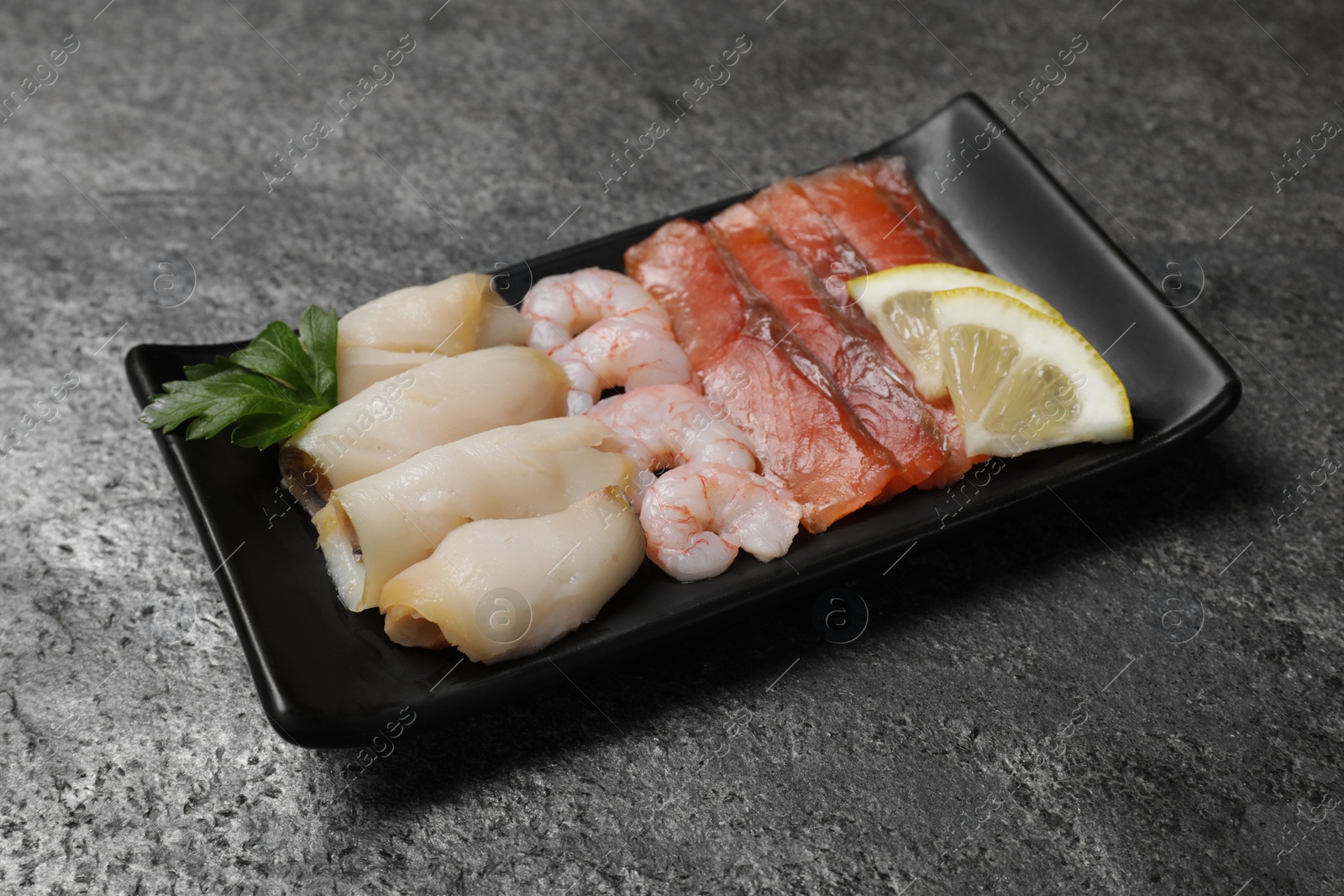 Photo of Sashimi set served with lemon and parsley on light grey table