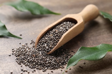 Scoop with chia seeds and fresh leaves on wooden table