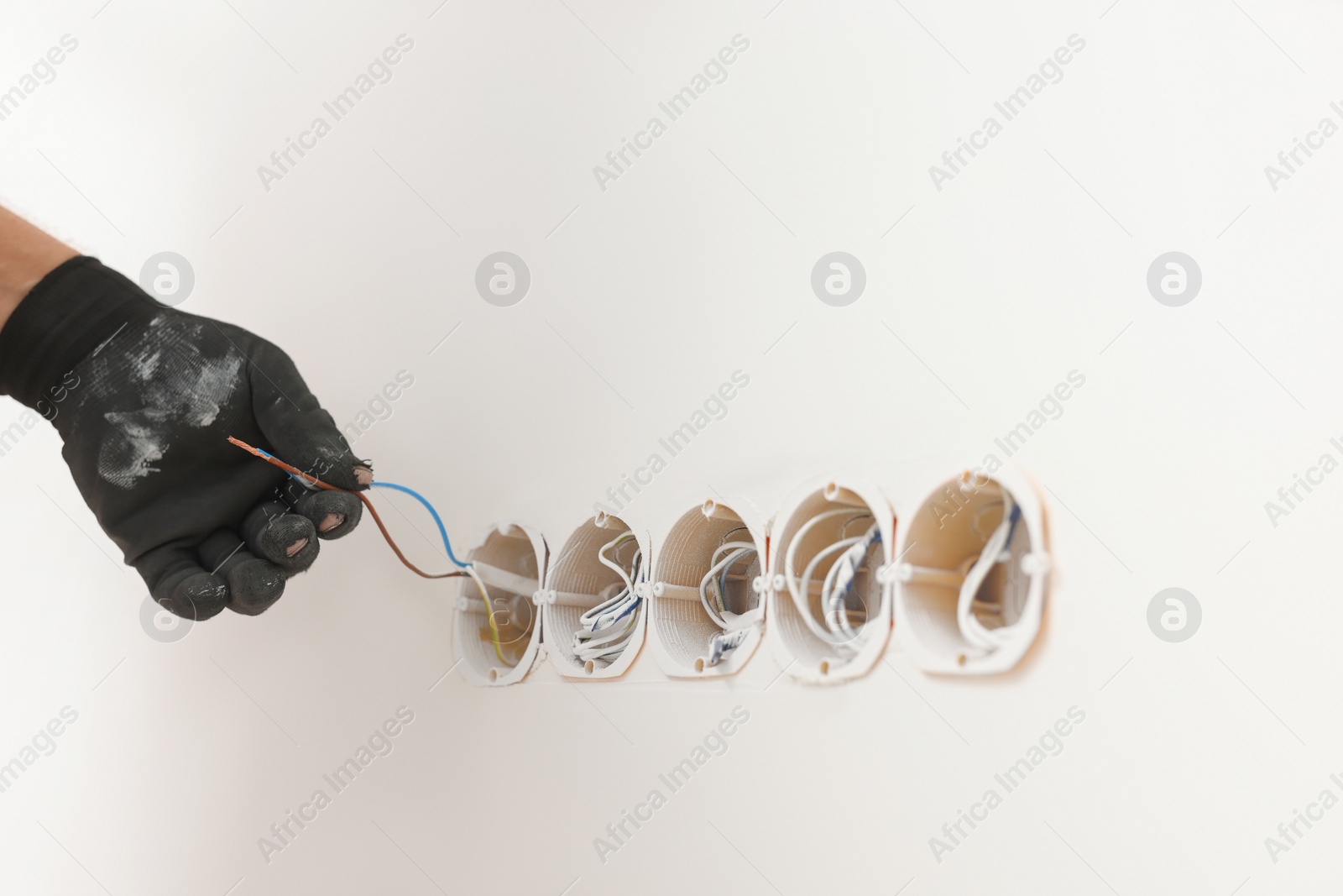 Photo of Handyman installing sockets in white wall, closeup