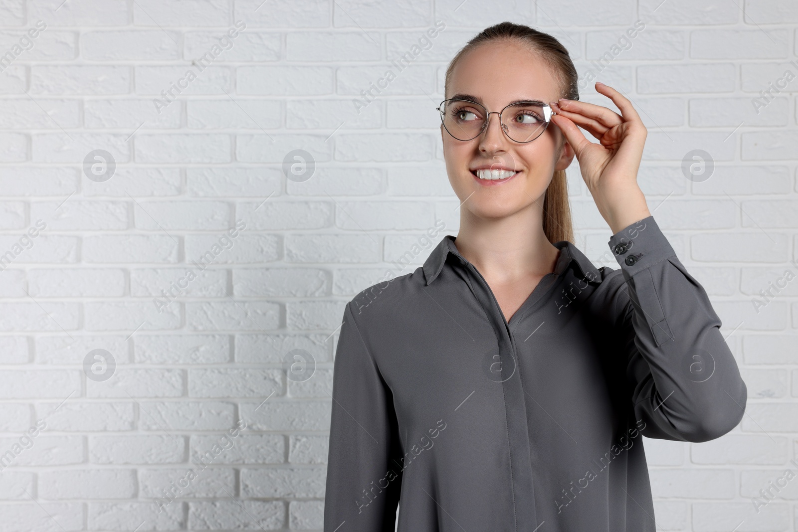 Photo of Portrait of happy young secretary near white brick wall, space for text