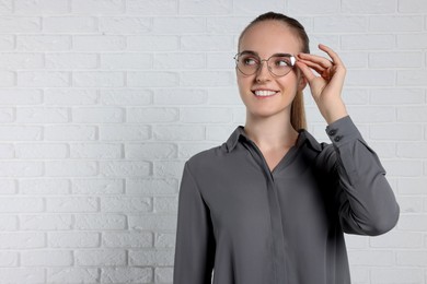 Portrait of happy young secretary near white brick wall, space for text