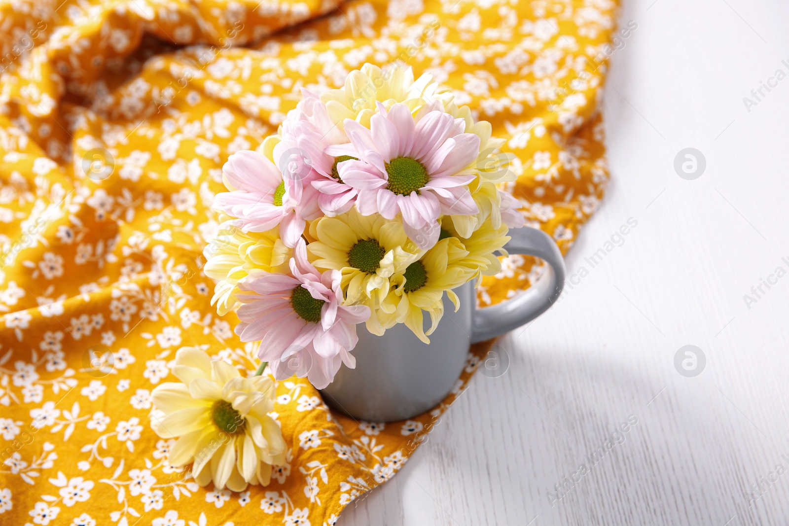 Photo of Cup with beautiful flowers on orange printed cloth. Good morning