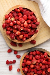Photo of Fresh wild strawberries in bowls on white wooden table, flat lay