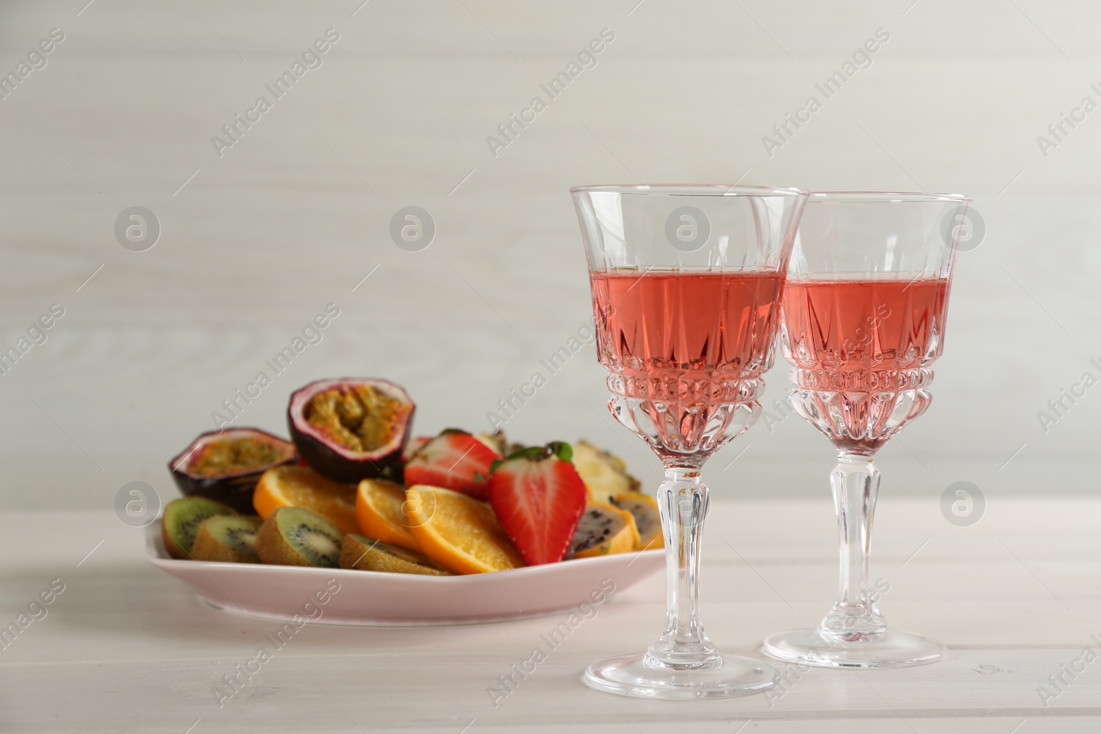 Photo of Delicious exotic fruits and glasses of wine on white wooden table