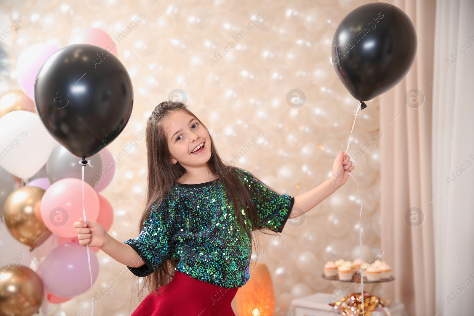 Photo of Happy little girl with balloons in beautifully decorated room at home. Birthday celebration