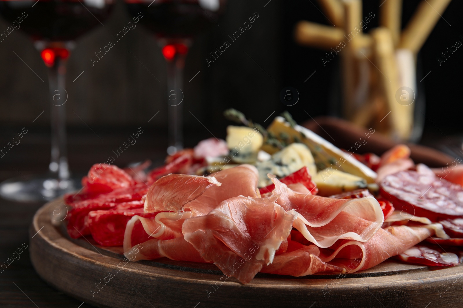 Photo of Tasty prosciutto with other delicacies served on table, closeup