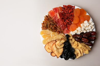 Photo of Plate with different dried fruits on white background, top view. Space for text