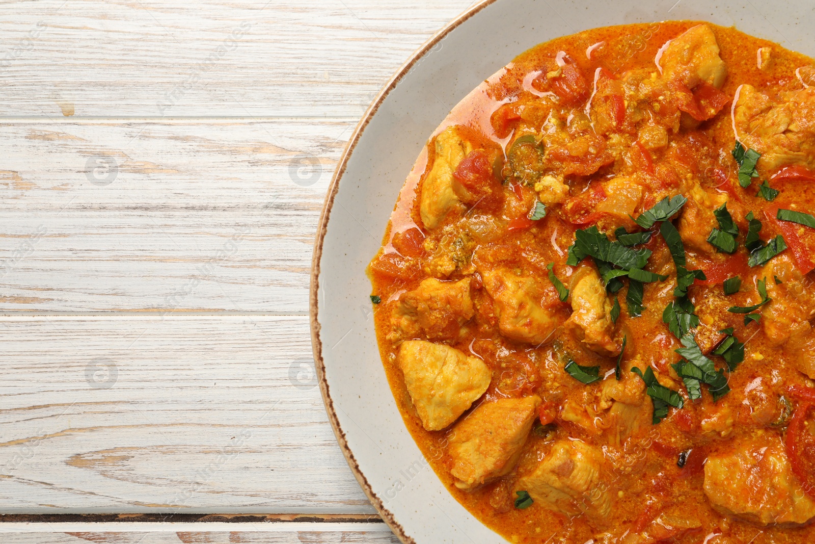 Photo of Delicious chicken curry on wooden table, top view. Space for text