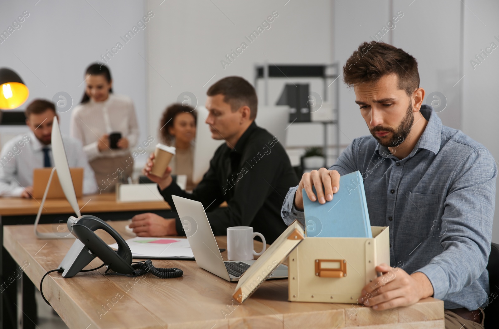 Photo of Dismissed man packing stuff into box at office