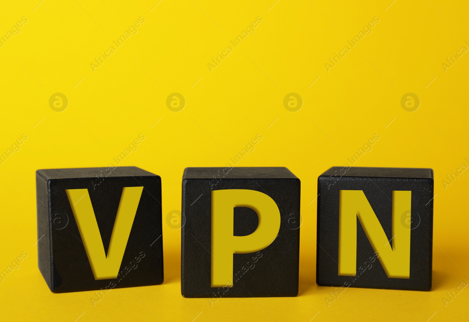 Image of Black cubes with acronym VPN on yellow background, closeup view