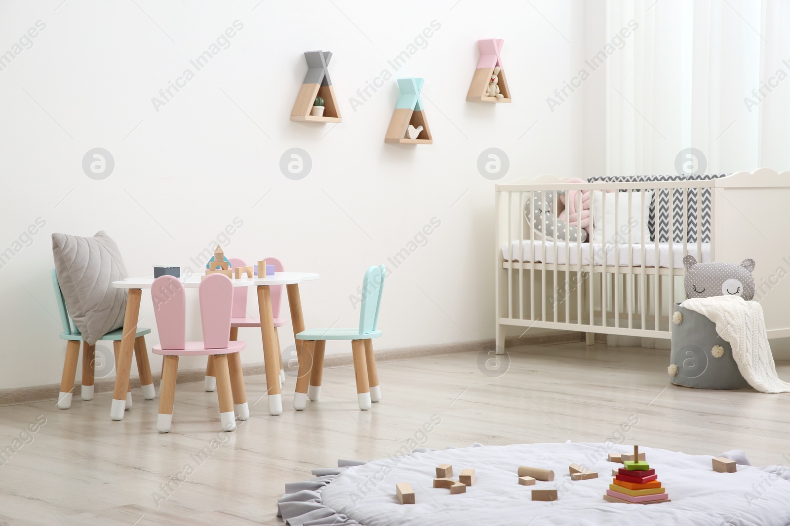 Photo of Cute baby room interior with cot and little table