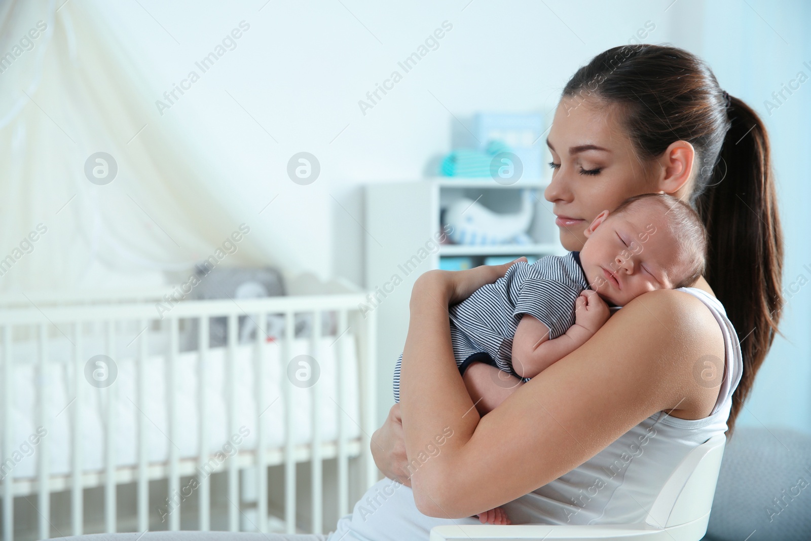 Photo of Young woman with her newborn baby at home. Space for text