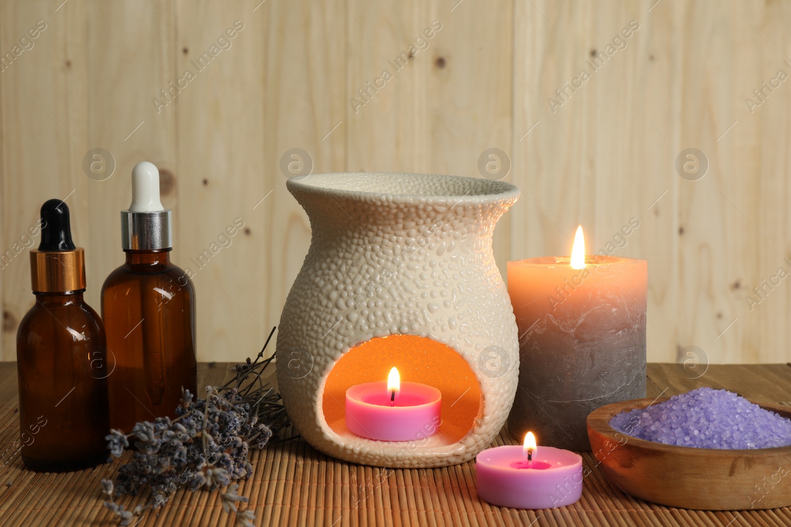 Photo of Aromatherapy. Scented candles, bottles, lavender and sea salt on bamboo mat