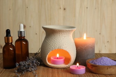 Photo of Aromatherapy. Scented candles, bottles, lavender and sea salt on bamboo mat