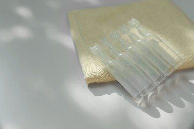 Photo of Single dose ampoules of sterile isotonic sea water solution and towel on white table, closeup. Space for text