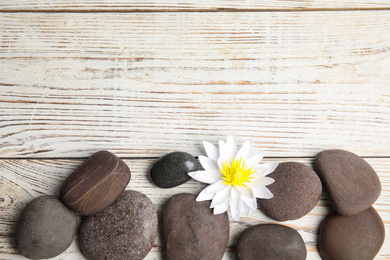 Photo of Stones with lotus flower and space for text on white wooden background, flat lay. Zen lifestyle
