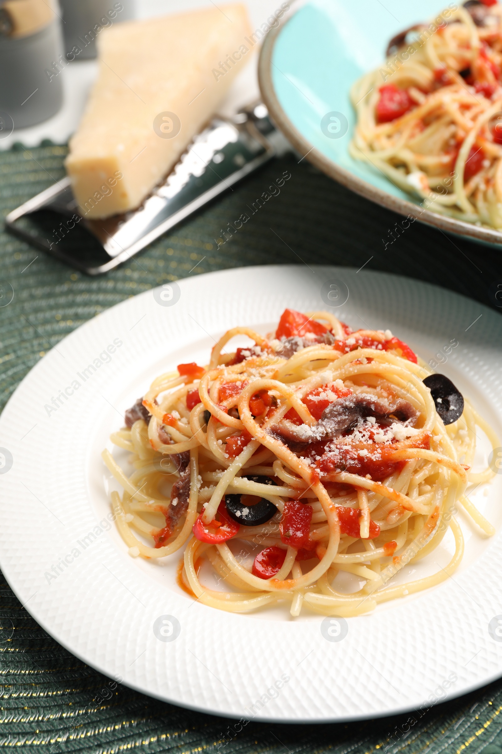 Photo of Delicious pasta with anchovies, tomatoes and parmesan cheese served on table, closeup