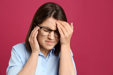 Photo of Young woman suffering from migraine on crimson background