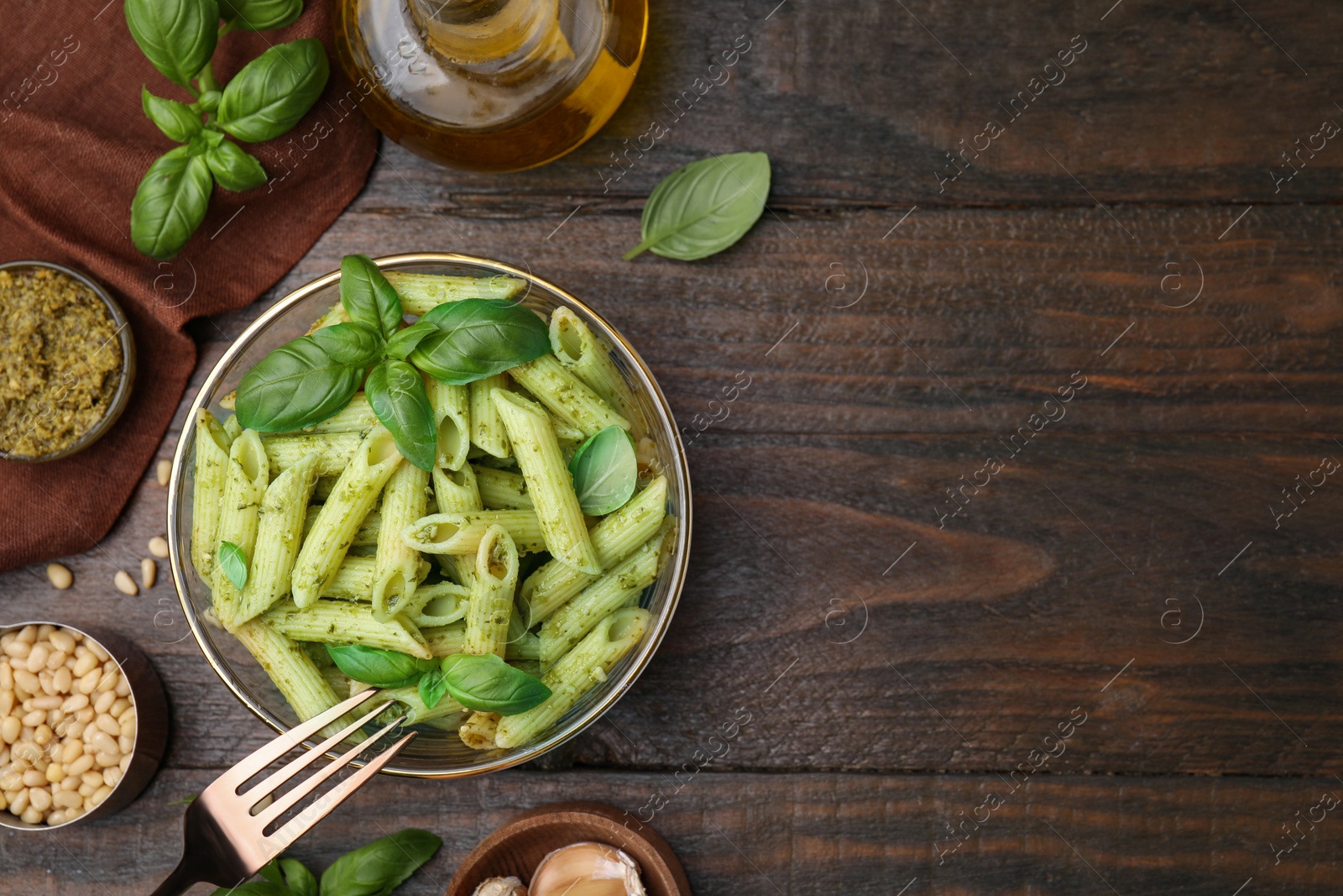 Photo of Delicious pasta with pesto sauce and ingredients on wooden table, flat lay. Space for text