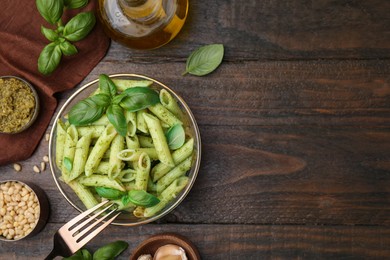 Photo of Delicious pasta with pesto sauce and ingredients on wooden table, flat lay. Space for text