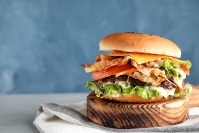 Photo of Tasty burger with bacon served on table. Space for text