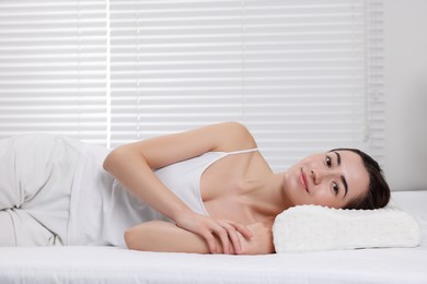 Photo of Woman lying on orthopedic pillow at home