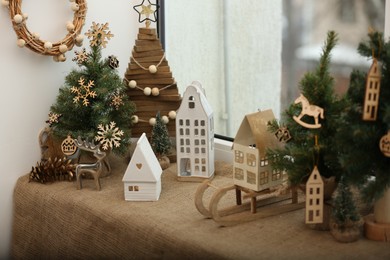 Photo of Beautiful window sill decorated for Christmas with small houses and fir trees indoors